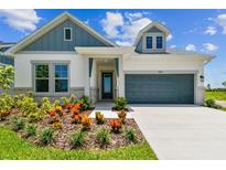 Charming home exterior showcases a well-manicured lawn, beautiful flowerbeds and a gray two-car garage at 5283 Everlong Dr, Apollo Beach, FL 33572