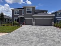 Inviting gray two-story home with a brick paver driveway and a two-car garage at 4319 Pullet Ct, Bradenton, FL 34211
