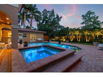 Outdoor living area featuring a pool, hot tub, and lush garden at dusk at 1124 Seville Ne Ln, St Petersburg, FL 33704