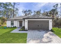 Charming home featuring a gray roof, a two-car garage, and a well-manicured lawn at 1150 Huntington St, North Port, FL 34288