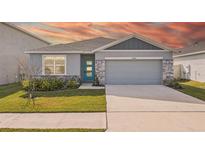Charming single-story home featuring a light gray exterior, stone accents, a blue front door and a two-car garage at 31814 Oyster Trellis Ln, Wesley Chapel, FL 33545