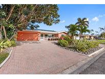 Charming single-story home featuring a lush landscaped yard, brick driveway, and solar panels on the roof at 5166 39Th S St, St Petersburg, FL 33711