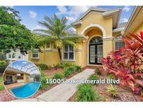 Inviting yellow home featuring a black double door entrance, lush landscaping, and a pool view on the side at 15005 Lake Emerald Blvd, Tampa, FL 33618
