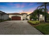 Beautiful home with a brick driveway, well-manicured landscaping, and a tile roof at sunset at 30715 Tumbleberry St, Wesley Chapel, FL 33543