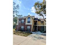 A two-story brick and siding condominium with a peaked roof and several windows at 8702 Mallard Reserve Dr # 104, Tampa, FL 33614