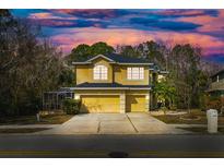 Charming two-story home with a three car garage and a beautifully landscaped yard under a dramatic twilight sky at 587 Lakewood Dr, Oldsmar, FL 34677