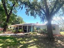 Charming one-story home featuring mature trees, brick accents, and a cozy covered porch entrance at 3009 Jim Johnson Rd, Plant City, FL 33566
