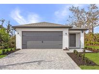 Charming single-story home with a gray brick driveway, gray garage door, and well-maintained landscaping at 4743 Michaler St, North Port, FL 34286