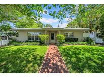 Charming single-story home with a well-maintained lawn and brick walkway, shaded by mature trees, offering curb appeal at 216 21St Ne Ave, St Petersburg, FL 33704