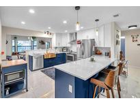 Open kitchen featuring an island with seating, stainless steel appliances, and marble countertops at 1753 Lucas Dr, Clearwater, FL 33759