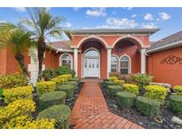 Inviting front entrance with a beautiful red brick walkway and colorful landscaping at 4534 Cozzo Dr, Land O Lakes, FL 34639