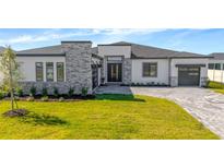 Stunning single-story home features a stone facade, well-manicured lawn, and a modern driveway at 8347 Golden Beach Ct, Parrish, FL 34219