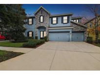 Charming two-story home with a three car garage, stone accents, black shutters, and lovely landscaping at 10825 Charmwood Dr, Riverview, FL 33569