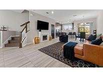 Open-concept living room with fireplace, large TV, tile floors, and view of the kitchen and dining area at 29913 Southwell Ln, Wesley Chapel, FL 33543