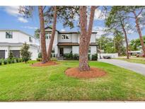 Charming two-story home featuring a lush green lawn, mature trees, and a welcoming entrance at 4224 W Kensington Ave, Tampa, FL 33629