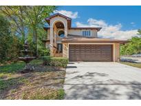Charming two-story home with an arched entryway, complemented by a beautiful fountain and manicured landscaping at 513 Suwanee Cir, Tampa, FL 33606