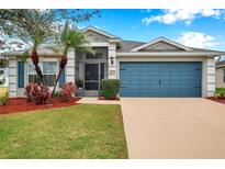 Charming single-story home featuring a well-maintained lawn, colorful landscaping, and a vibrant blue garage door at 5720 107Th E Ter, Parrish, FL 34219