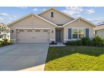 Charming single-story home featuring a two-car garage and well-maintained lawn with blue shutters and a welcoming entrance at 12143 Kingsley Trl, Parrish, FL 34219