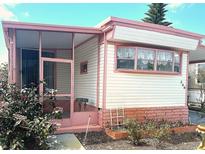 Charming home with pink accents, a screened porch, and a well-maintained front yard at 9790 66Th N St # 248, Pinellas Park, FL 33782