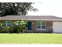 Charming single-story home with a well-manicured lawn, complemented by lush greenery and a welcoming blue front door at 1215 Oakhill St, Seffner, FL 33584