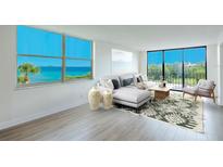 Bright living room features hardwood floors, a modern sofa, and expansive windows with ocean views at 100 Oakmont Ln # 309, Belleair, FL 33756