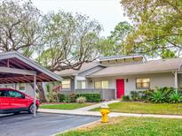 Charming single-story home boasts a vibrant red door, manicured lawn, and convenient carport at 40 Aster Pl, Oldsmar, FL 34677