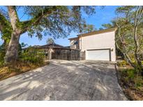 Beige two-story home with a two-car garage and a gated driveway, shaded by mature trees at 1110 W Coral St, Tampa, FL 33602