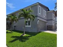 Charming exterior elevation features a gray stucco and stone exterior, attached garage, and manicured lawn at 1600 Pennsylvania Ne Ave, St Petersburg, FL 33703