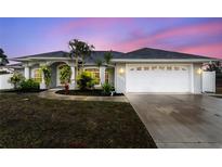 Charming single-story home with arched entryway, two-car garage, and tropical landscaping at dusk at 5366 Hader Rd, North Port, FL 34288