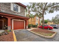 Attached garage with red door and stone exterior, providing convenient parking and curb appeal at 2254 Chianti Pl # 68, Palm Harbor, FL 34683