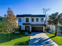 Modern two-story home with a dark garage door, a stone accent wall, and a paved driveway at 818 W Adalee St, Tampa, FL 33603