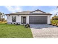 Charming single-story home featuring a two-car garage and well-manicured front lawn with paver driveway at 3560 Bellefonte Ave, North Port, FL 34286