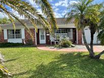 Charming front yard with well-maintained lawn, brick facade, and palm trees at 3722 Haven Dr, New Port Richey, FL 34652