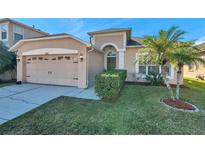 Charming home featuring a well-manicured lawn, palm tree, and a two-car garage at 4506 Mapletree Loop, Wesley Chapel, FL 33544