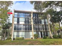 Multi-story condominium with large windows and black metal railing on balconies surrounded by mature landscaping and blue sky at 90 S Highland Ave # 423, Tarpon Springs, FL 34689