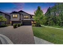 Elegant two-story townhome with a brick driveway and well-manicured landscaping at dusk at 4899 Isola Ct, Wesley Chapel, FL 33543