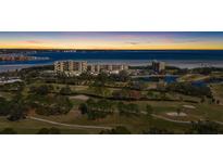 Beautiful aerial view of waterfront condos, lush golf course, and stunning bay at sunset at 2617 Cove Cay Dr # 604, Clearwater, FL 33760