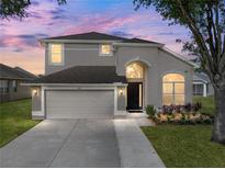 Charming two-story home featuring a well-manicured lawn, a two-car garage, and neutral stucco exterior at 4351 Highcroft Dr, Wesley Chapel, FL 33545
