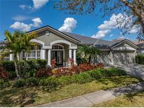 Beautiful home featuring a lush landscaped front yard, arched entryway, and a three-car garage at 6307 Bridgevista Dr, Lithia, FL 33547