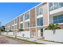 Modern townhome exterior features large windows, light wood accents, and a white privacy fence at 2702 N Woodrow Ave # 2, Tampa, FL 33602