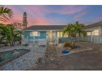 Charming coastal home featuring a fenced yard, white picket fence, palm trees and decorative stone landscaping at 421 77Th Ave, St Pete Beach, FL 33706