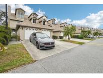 Charming townhome with attached garage, dormer windows, well-maintained landscaping, and driveway with grey Volkswagen parked at 2794 Countryside Blvd # 1, Clearwater, FL 33761
