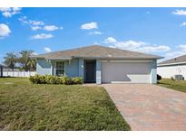 Charming light blue single-story home with a brick driveway and well-maintained lawn at 1203 Desmond St, Port Charlotte, FL 33952