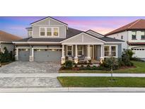 Charming two-story home with a well-manicured lawn, a brick driveway, and a covered front porch with chairs at 14215 Swiss Bridge Dr, Riverview, FL 33579