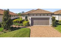 Lovely single-story home showcasing a tile roof, two-car garage, and brick-paved driveway complemented by manicured landscaping at 11125 Callisia Dr, Odessa, FL 33556
