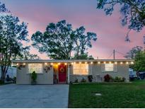 Charming home featuring string lights, a vibrant red door with a wreath, and a well-maintained front yard at 6145 55Th N Ave, St Petersburg, FL 33709