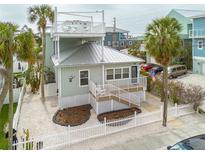 Charming coastal home with two stories, a metal roof, a deck and white picket fence at 106 7Th Ave, St Pete Beach, FL 33706