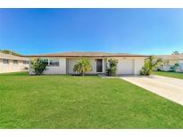 Charming single-story home with lush green lawn and mature landscaping under a clear blue sky at 10118 Hickory Hill, Port Richey, FL 34668