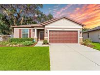 Charming single-story home featuring a well-manicured lawn, brown shutters, and an attached two-car garage at 15571 Stone House Dr, Brooksville, FL 34604
