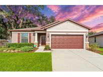 Charming one-story home featuring a well-manicured lawn, lush landscaping, and a two-car garage at 15571 Stone House Dr, Brooksville, FL 34604
